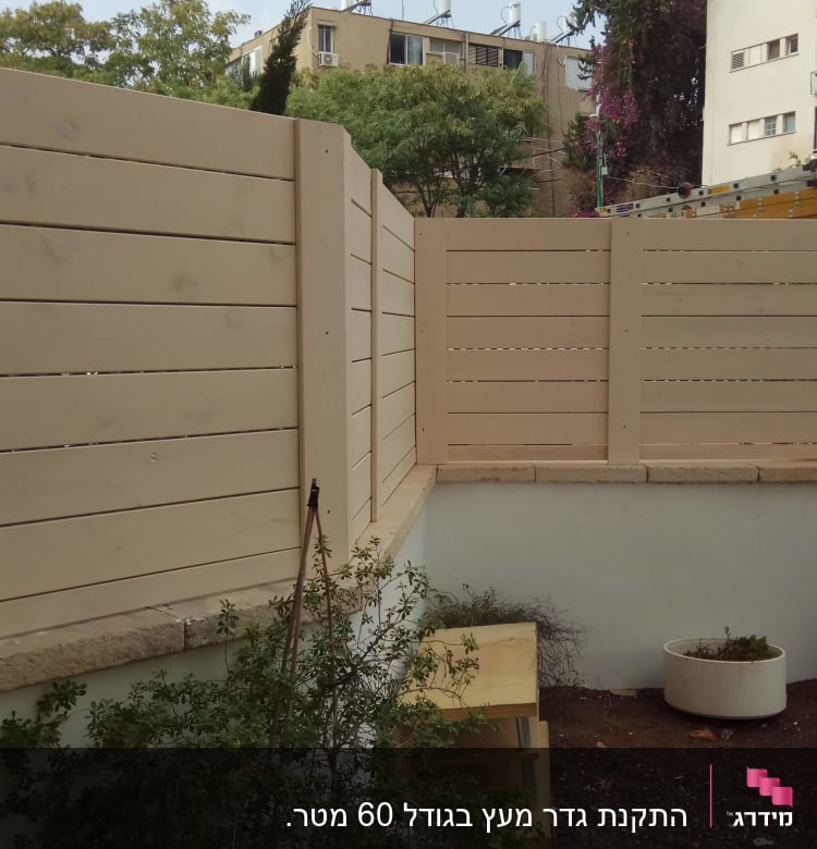 גדר עץ בהירה עם עציצים בגינה